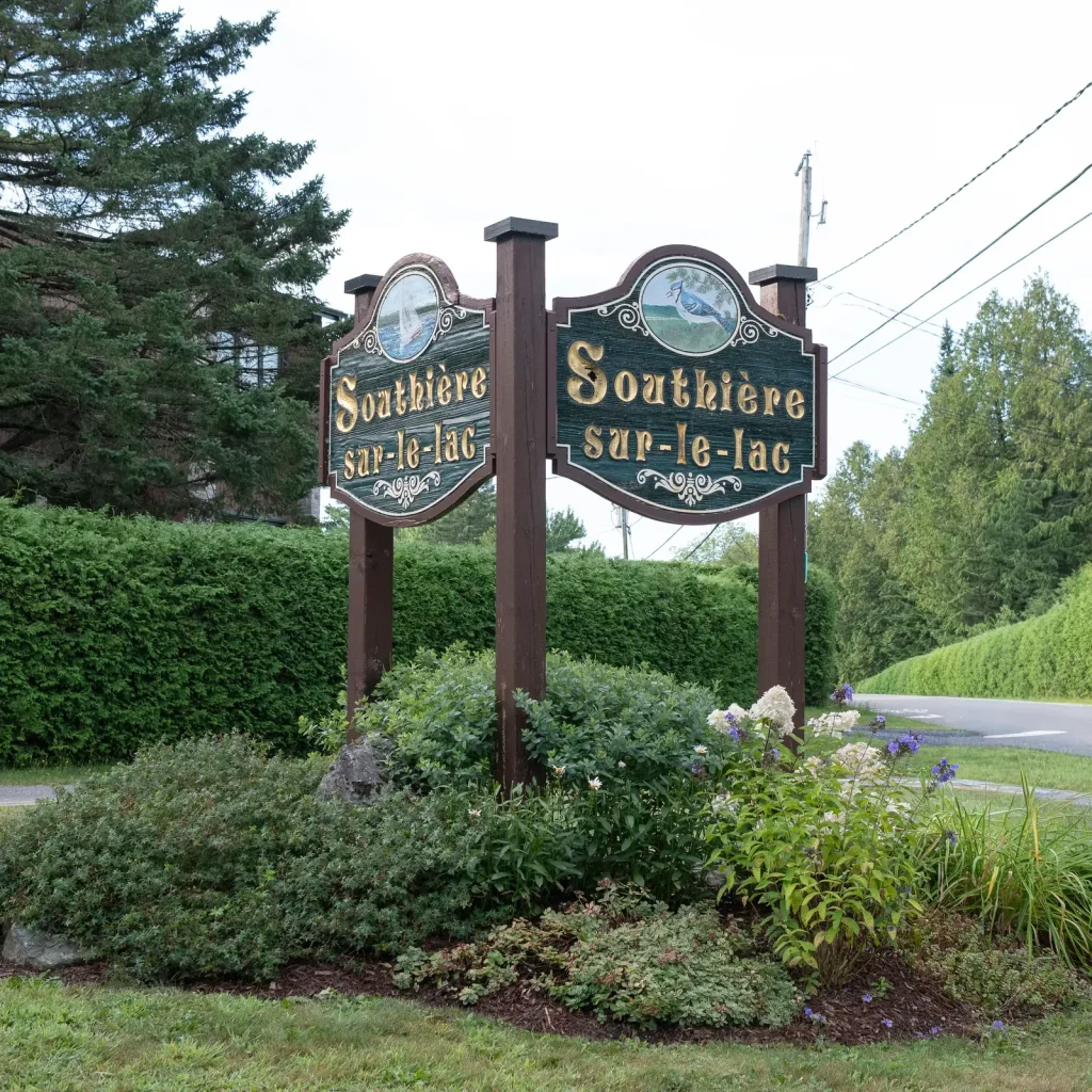 Enseigne en bois sculpté « Southière-sur-le-Lac » à l’entrée du quartier, à Magog