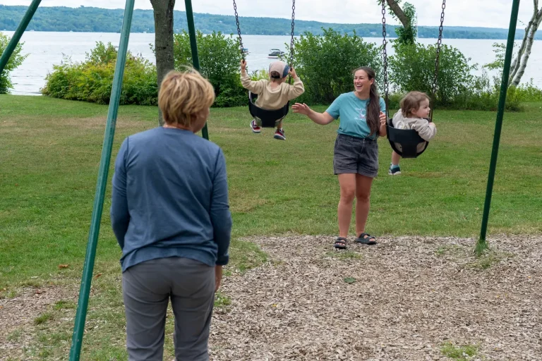 Enfants sur les balançoires du parc, au bord du lac, avec leurs proches