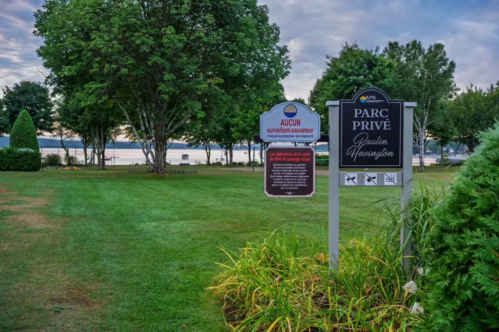 Panneau du parc privé Paulin-Hovington de l’APS, avec la pelouse et le lac en arrière-plan